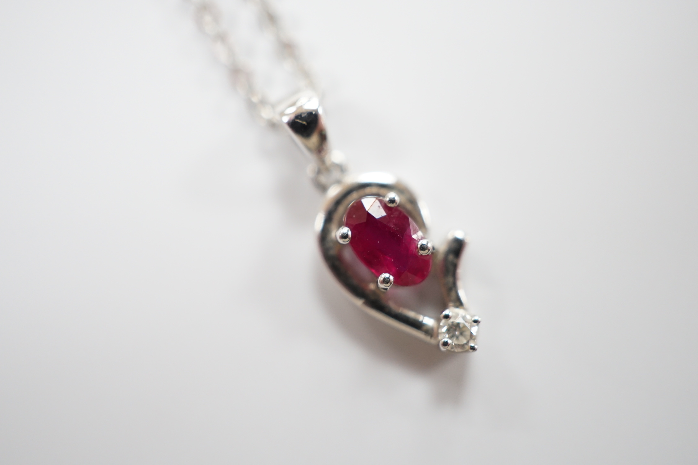 A modern 750 white metal, ruby and diamond set pendant, 9mm, on a 750 white metal chain, 42mm, gross weight 2.6 grams.